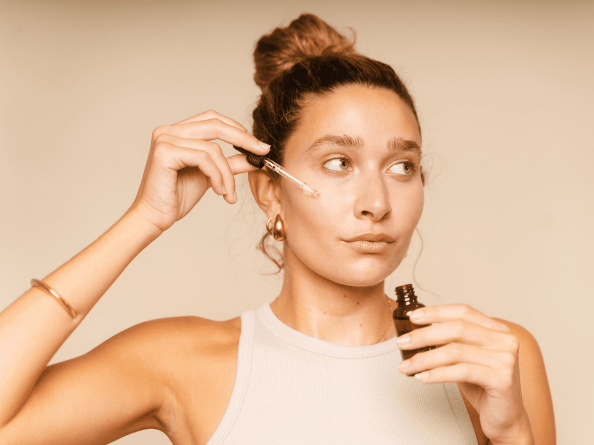 Woman applying a serum to her face as part of a daily skincare routine for acne-prone skin in Tampa, FL